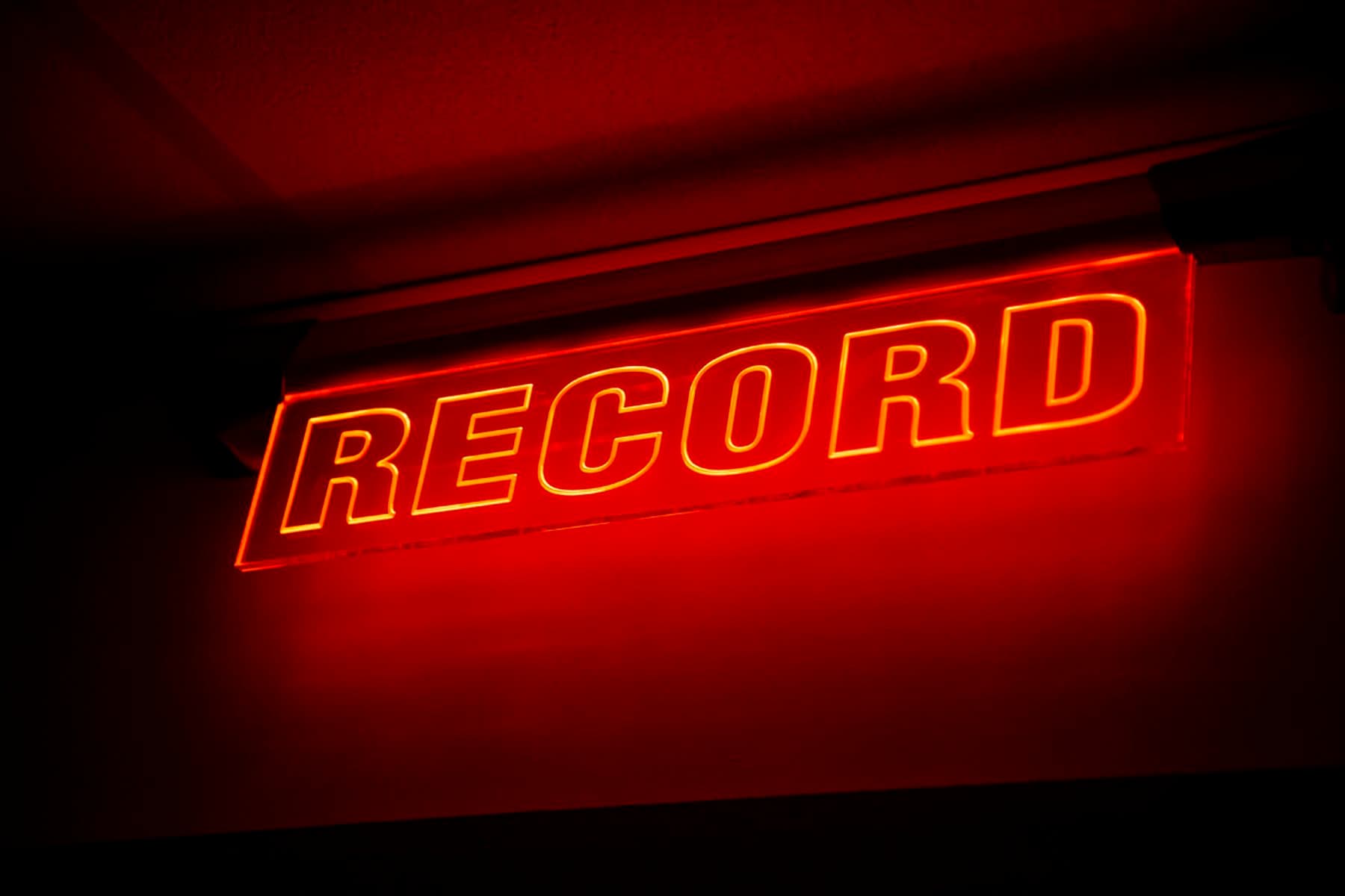 A photograph of a red neon lit sign stating “Record” in capital letters.