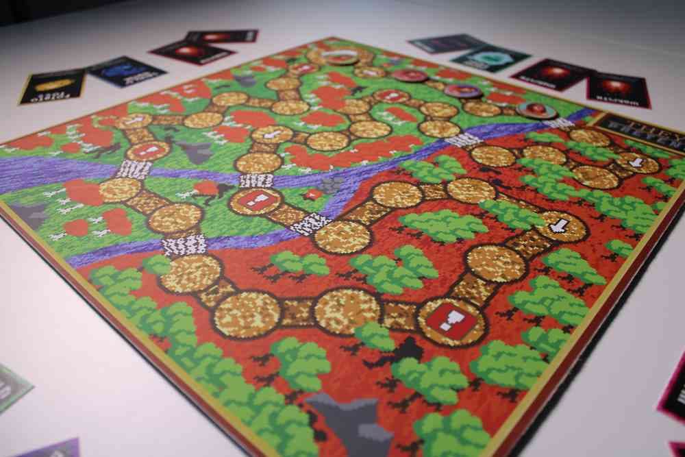 An image of a colourful board game with a pixilated map featuring pathways, trees and a river surrounded by various cards.
