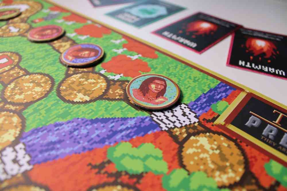 An image of a colourful board game with pixilated graphics, circular character tokens and cards with white text.