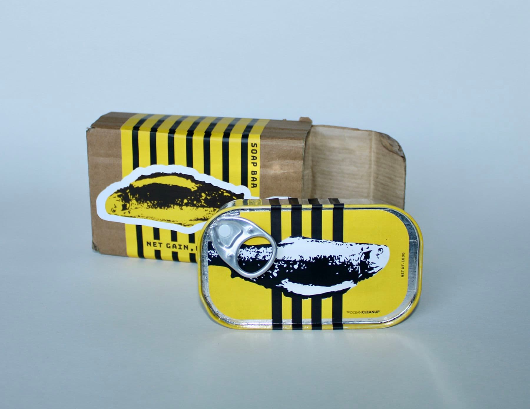 A photograph of packing design for a soap bar, in the form of a small tin of fish. The design is bold yellow and black, with an illustration of a fish.