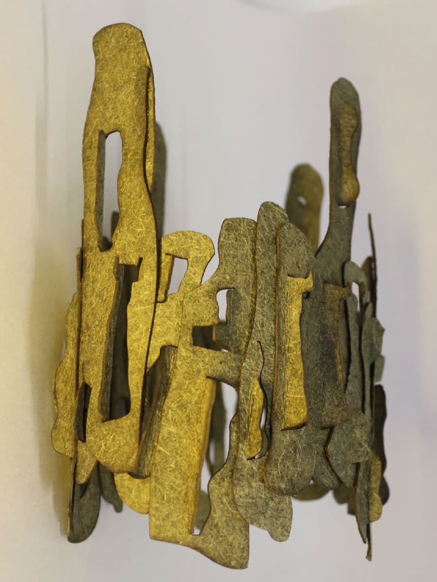 Abstract sculpture with interlocking shapes in gold and bronze tones, forming an layered pattern.