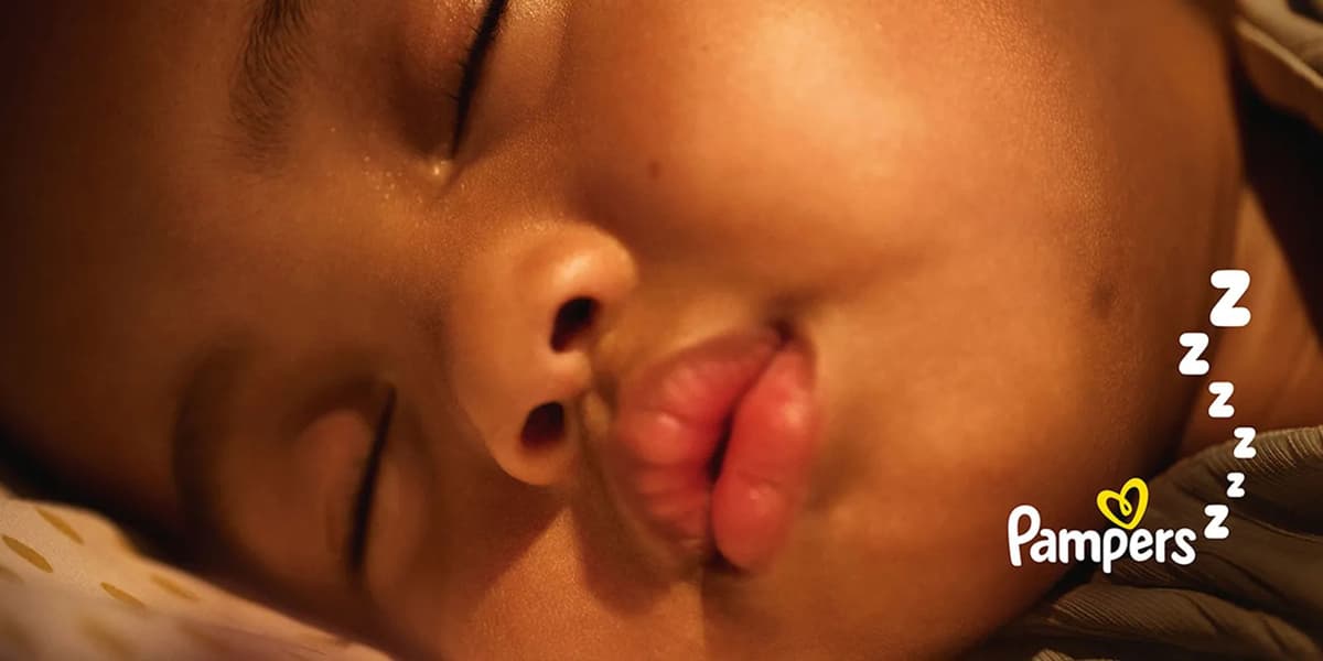 Close-up of a peacefully sleeping baby with the Pampers logo and "Zzz" symbols on the side.