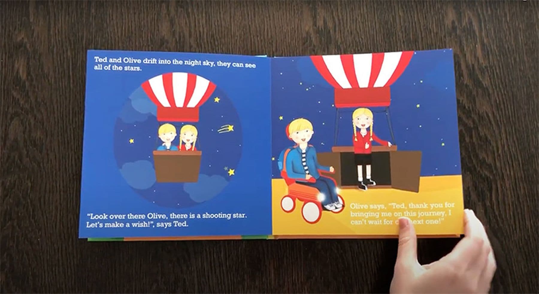A photograph of an open children's book showing illustrations of two kids in a hot air balloon at night, with text about seeing stars and making a wish.